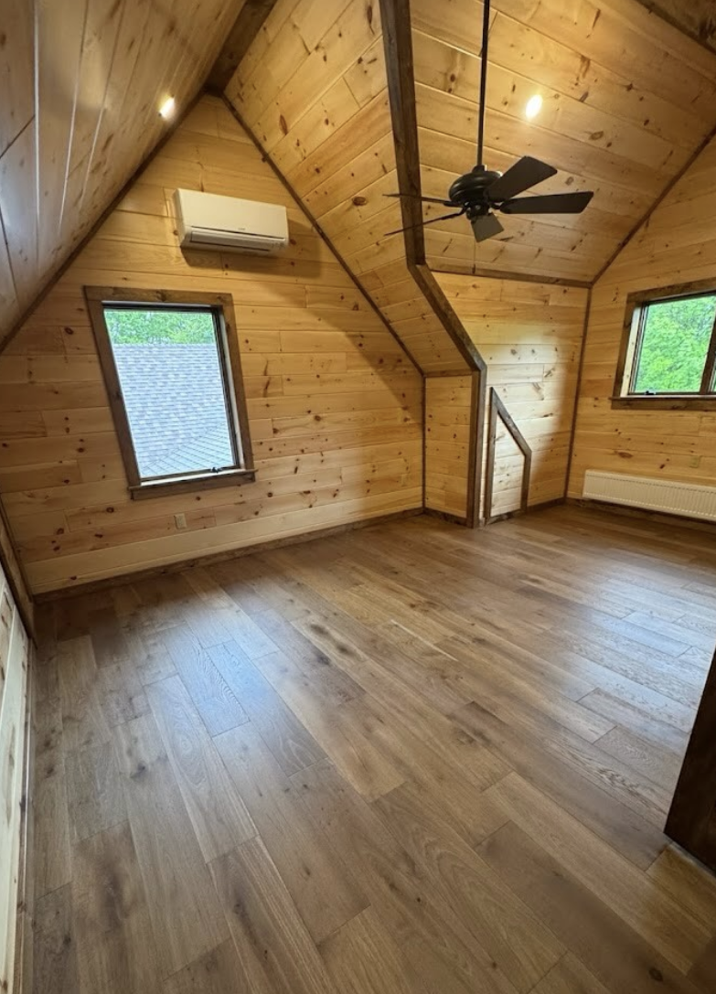 Finished pine attic bonus room with dust-free floors and clean windows after post-construction cleaning