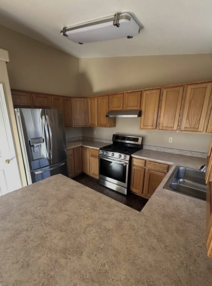 Oak cabinet kitchen with wiped counters, cleaned stove, and polished sink after a move-out clean