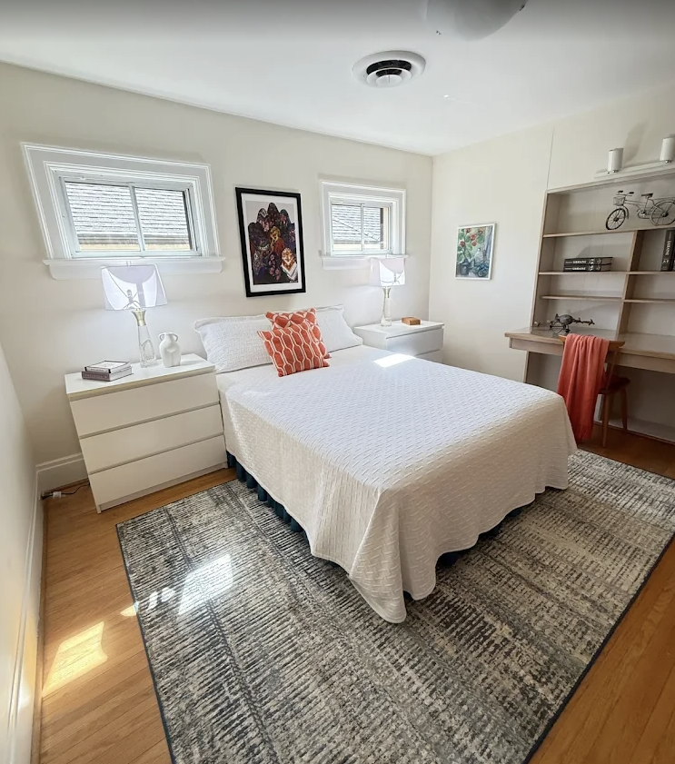 Bright guest bedroom with crisp white bedding, dusted shelves, and vacuumed rug